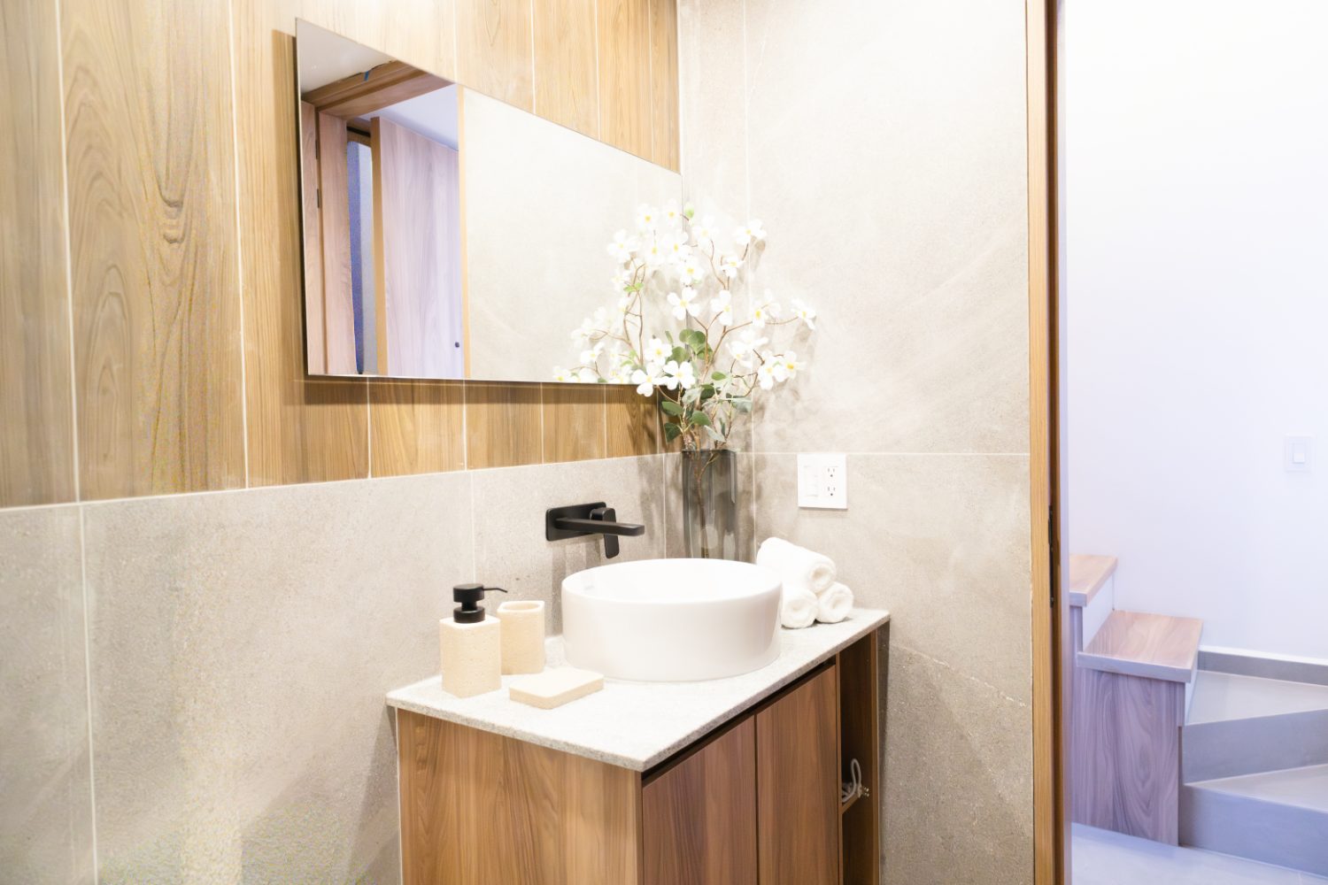 Baño con lavabo sobre cubierta y acabados en piedra y madera, modelo Gala